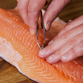 Pin-boning a fillet of salmon by hand